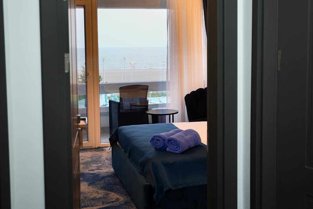 Cameră dublă cu ușa de balcon deschisă spre mare
